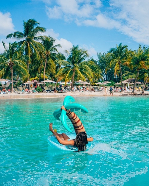 a woman at the beach relaxing on a palm tree floatie