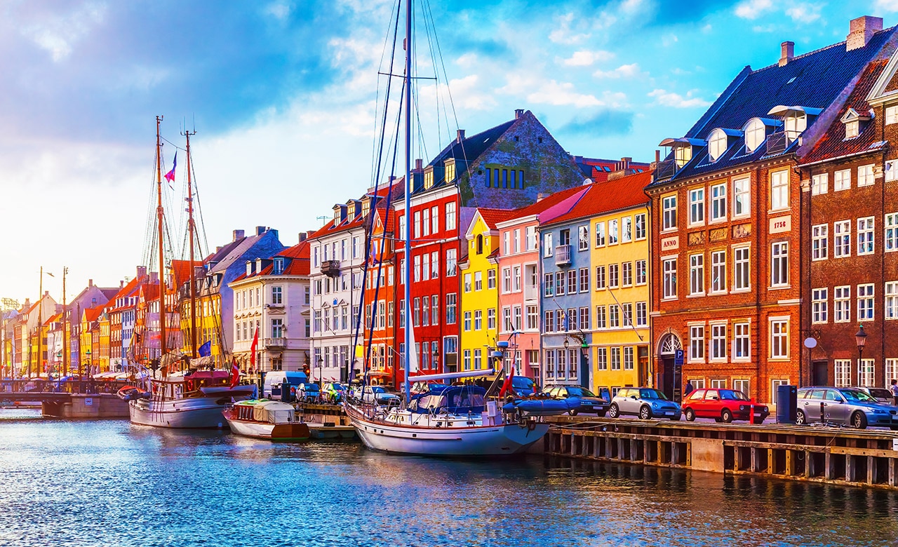 Scenic summer sunset view of Nyhavn pier with color buildings, ships, yachts and other boats in the Old Town of Copenhagen, Denmark