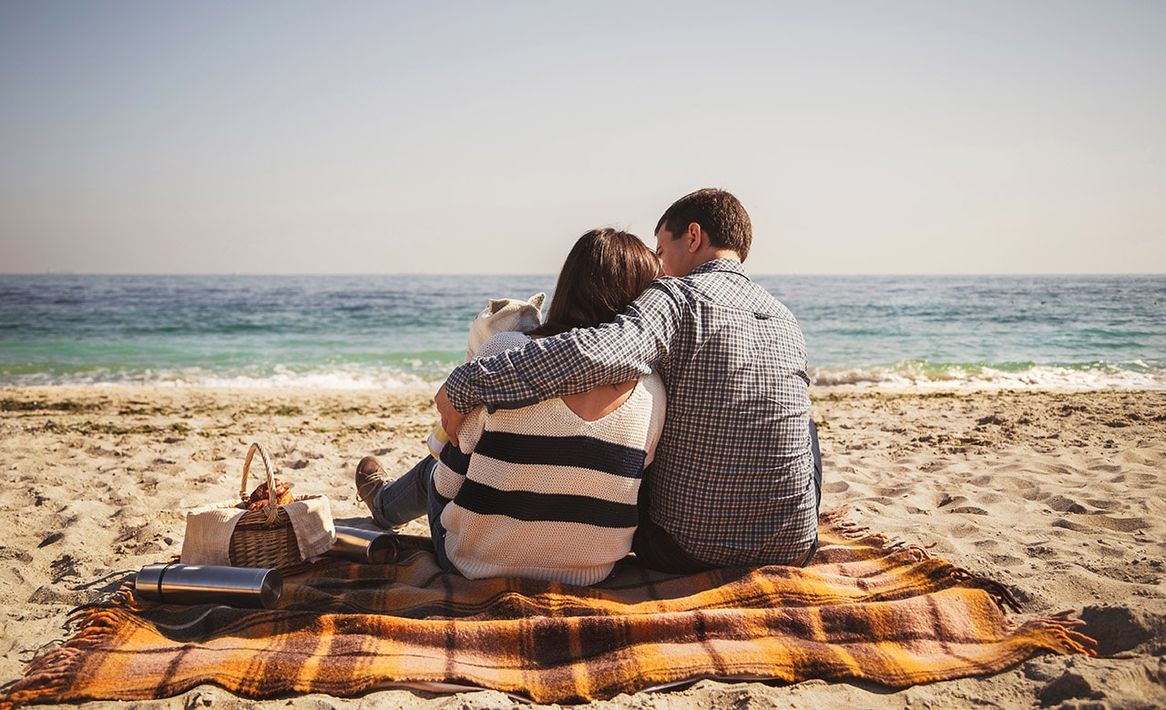 Young happy loving family with small child, enjoying time at beach sitting and hugging near ocean, happy lifestyle family concept.