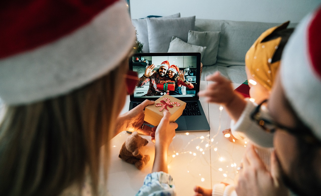 Family celebrating Christmas with their relatives respecting social distancing. They are doing a video call using a laptop to celebrate together. New normal during Coronavirus Covid-19 pandemic concept.