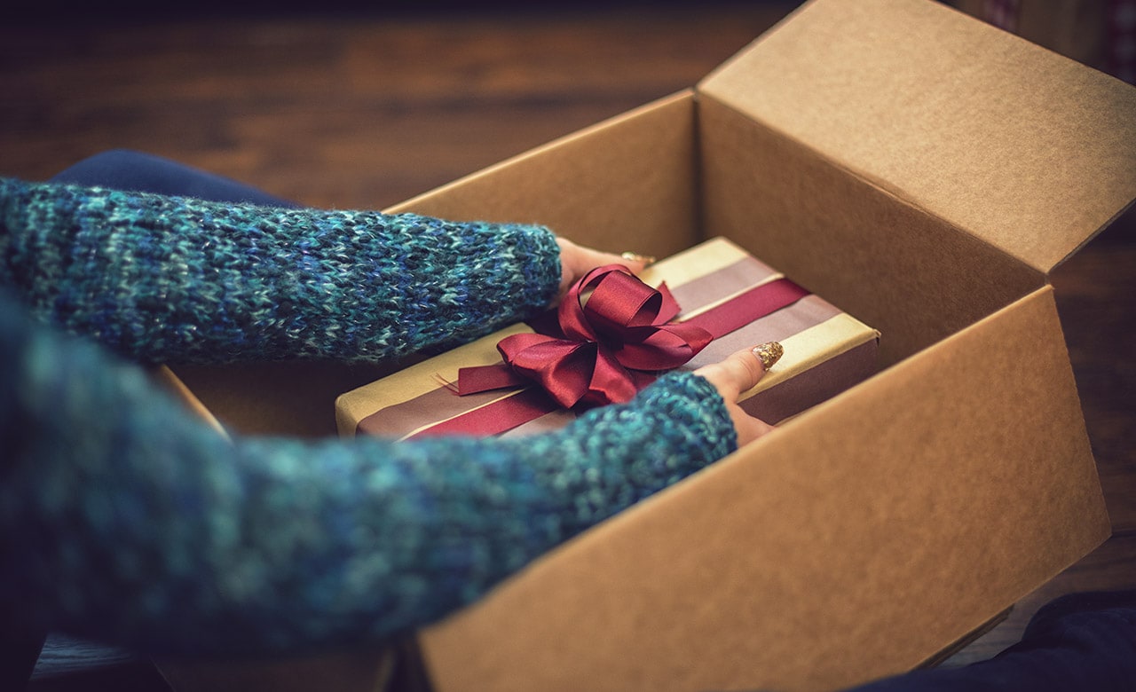 Young beautiful girl accepting and opening parcel with present box on Christmas