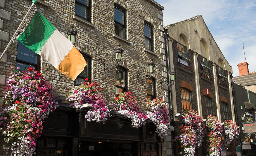 A stone pub in Dublin, Ireland with an Irish flag and flowers