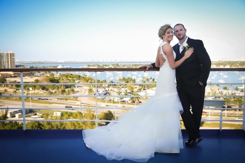 Newlyweds posing by a railing that overlooks a city landscape