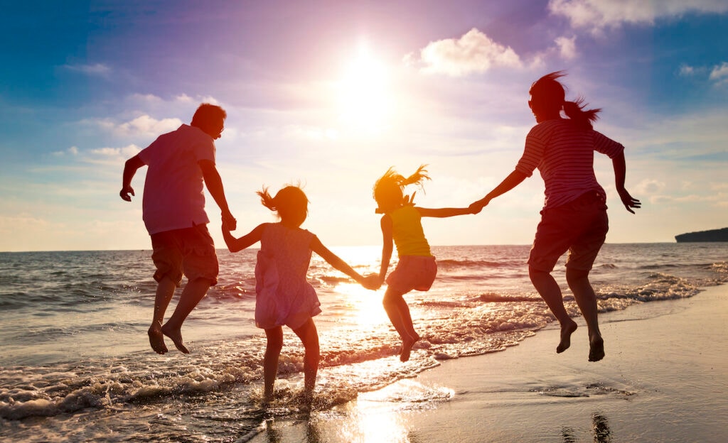 Family jumping along a beach coast