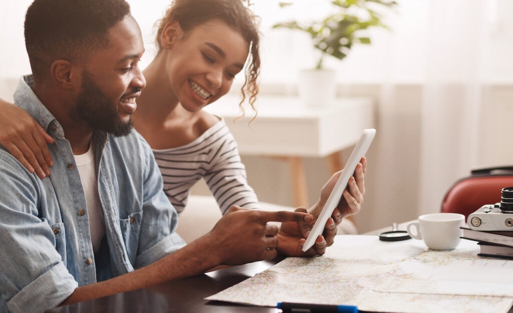 Couple browsing a tablet surrounded by travel items