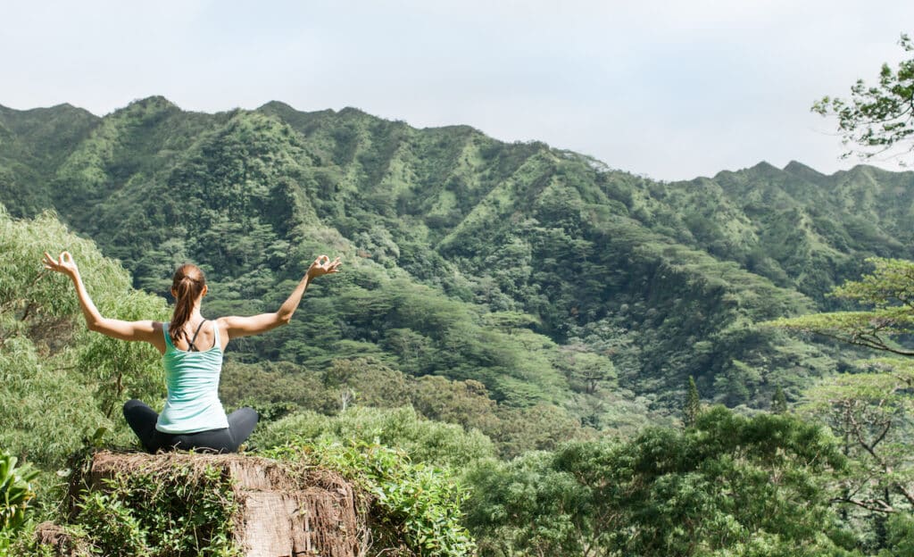 Woman meditating as she's surrounded by nature.