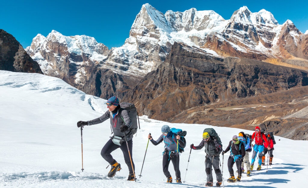 Line of adventurers walking along a snowy landscape.