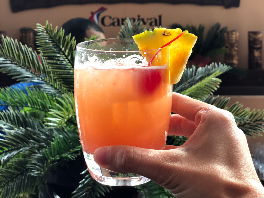 a hand holding a glass of Carnival Cruise's Red's Rum Treasure