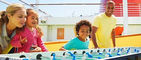 a man, a woman and two children playing foosball