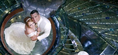 a newlywed couple posing for a photo next to a spiral staircase on a carnival cruise