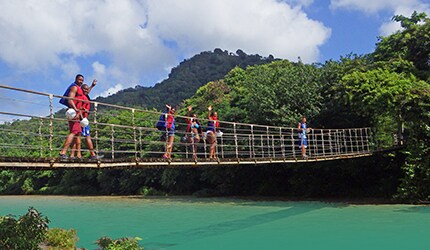 guests crossing wooden bridge during an excursion at rio de damajagua in amber cove