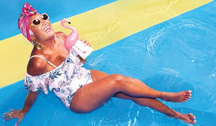 lady sunbathing with a pink flamingo drink in her hand