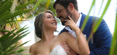 groom and bride looking at each other with palm fronds in the background