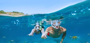 two kids snorkeling in the ocean with fish